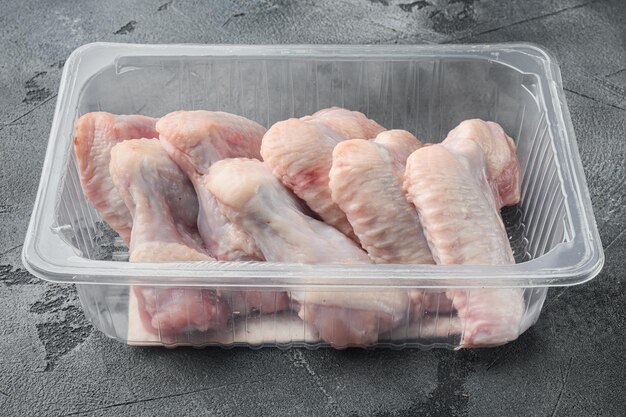 Fresh chicken wings spit in plastic vacuum pack set on gray stone background