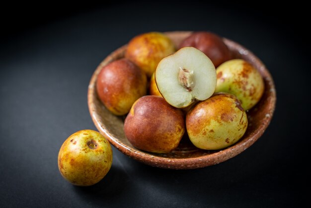 Fresh chinese jujube in a plate on black background