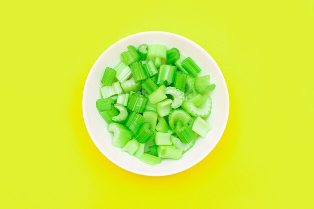 Fresh chopped celery peaces with water drops in white bowl