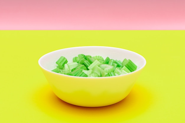 Fresh chopped celery peaces with water drops in white bowl