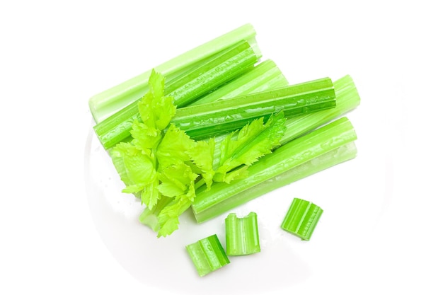 Fresh chopped celery sticks and slices with leaves and water drops isolated on white background