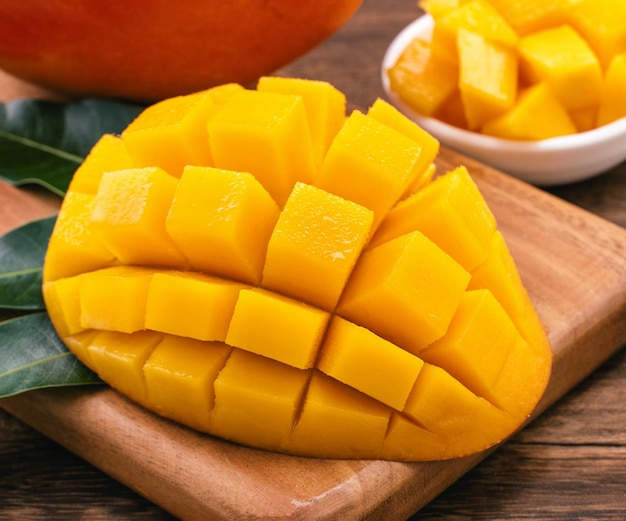 Fresh chopped mango cubes on wooden cutting board and rustic timber background Tropical summer fruit concept close up macro copy space