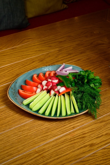 Fresh chopped vegetables on a wooden table. Appetizer of fresh tomato, cucumbers, radishes and herbs.Top view.The concept of healthy eating, diet, vegetarianism.