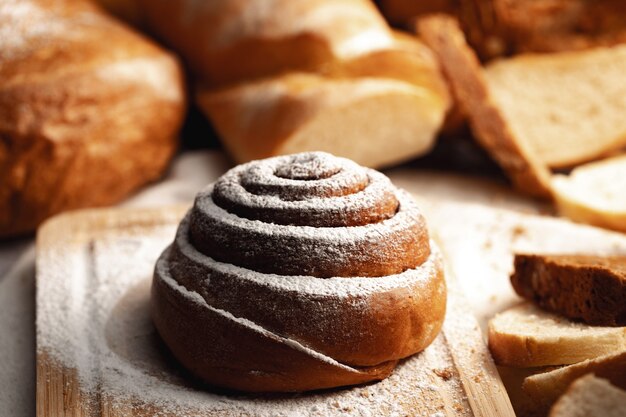 Fresh cinnamon bun roll with sugar powder on wooden board