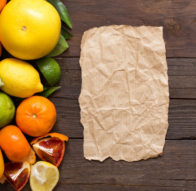 Fresh citrus fruits with craft paper on wood