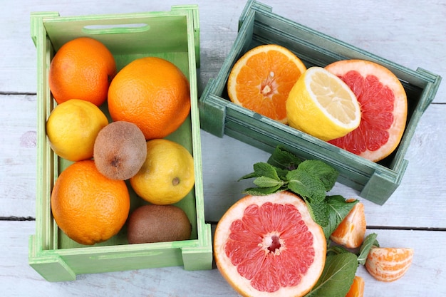 木製の背景の色に木製の箱に緑の葉を持つ新鮮な柑橘系の果物