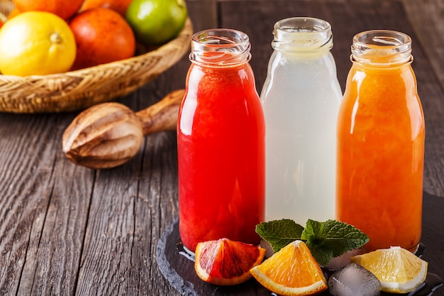 Fresh citrus juices on a dark wooden table.