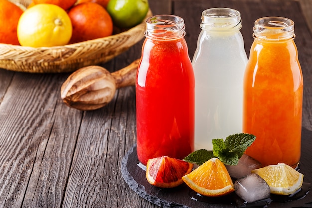 Fresh citrus juices on a dark wooden.