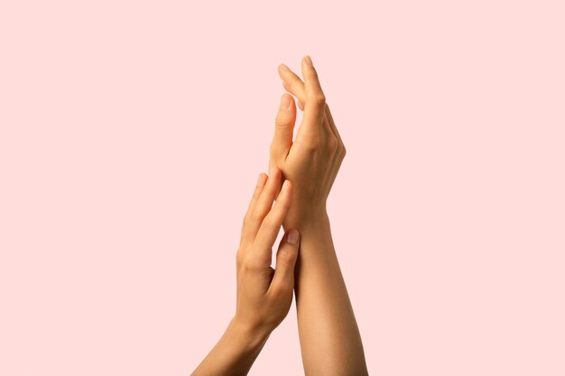 Fresh and clean hands skin with accurate neutral manicure on pink background