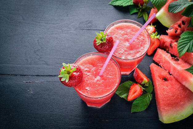 Fresh cocktail of watermelon and strawberries Mint ice On a wooden board Top view Free space for your text