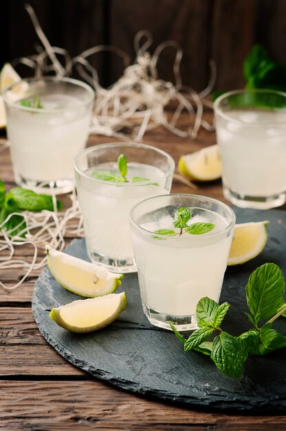 Fresh cocktail with lemon, ice and mint on the vintage table