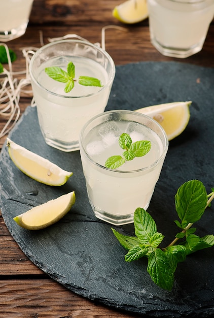 Fresh cocktail with lemon, ice and mint on the vintage table