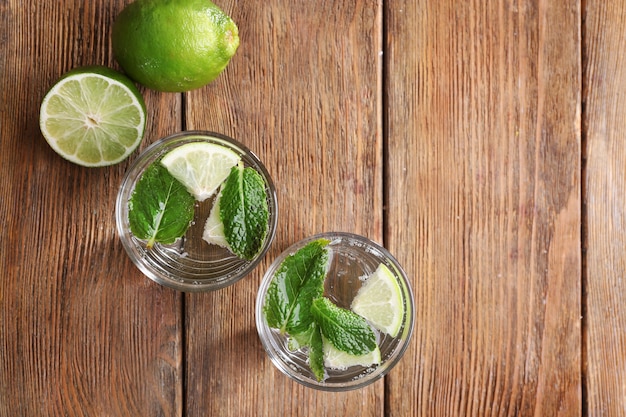 Fresh cocktails with mint, ice and lime on wooden table surface, view from above