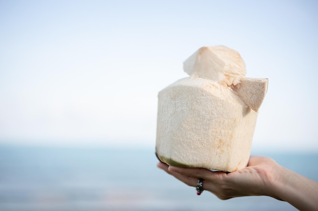 Fresh coconut cocktail in hand over ocean background.