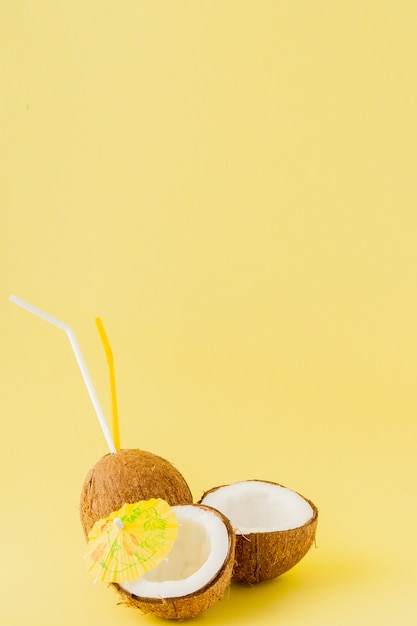 Fresh Coconut cocktail with a straws on yellow background, copy space