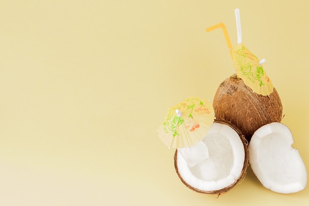 Fresh coconut cocktails with plastic straws on yellow background with copy space