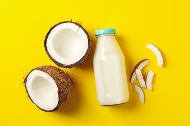 Fresh coconut and coconut milk on yellow background