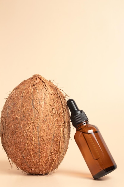 Fresh coconut and glass bottle of cosmetic oil on beige background Organic cosmetic concept