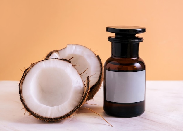 fresh coconut half and bottle of coconut oil mock up on orange background on marble white table