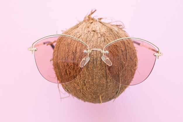 Photo fresh coconut wearing sunglasses on a bright pink background hello summer