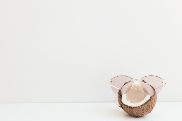 Fresh coconut wearing sunglasses on color background Hello summer