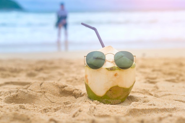 Cocco fresco con cannuccia sul concetto di viaggio e vacanze in spiaggia