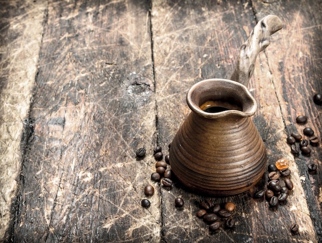 Fresh coffee in a clay turkey. On a wooden background.