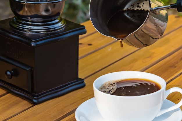 Fresh coffee from a cezve pouring in cup