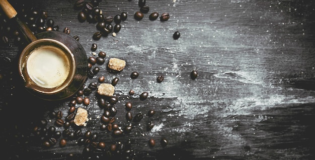 Fresh coffee pot with cane sugar and roasted grains on black chalkboard.