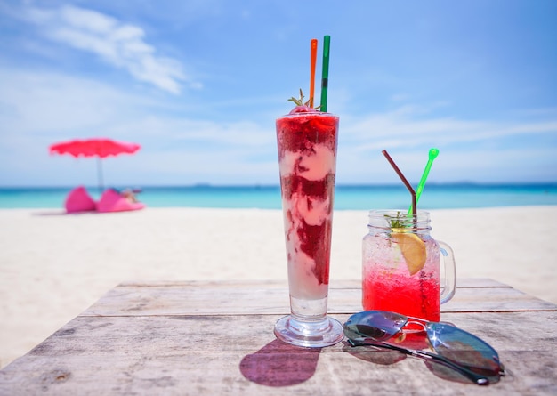 Fresh cold drink on wooden table and Summer blurred background of beach