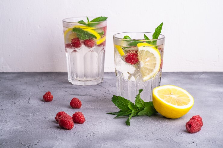 Photo fresh cold ice water drink with lemon, raspberry fruits and mint leaf in two faceted glasses