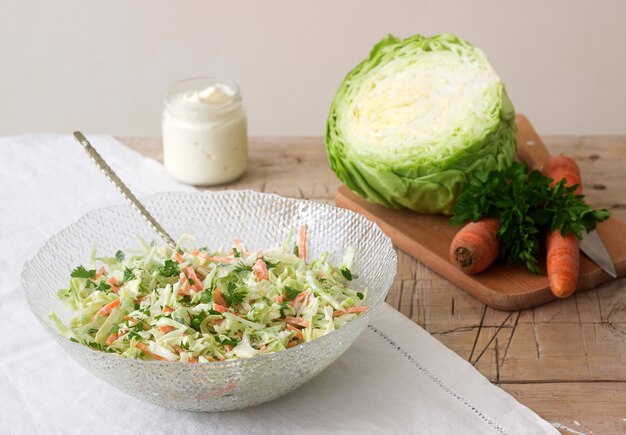 Fresh coleslaw salad in bowl and ingredients for salad. Rustic style.