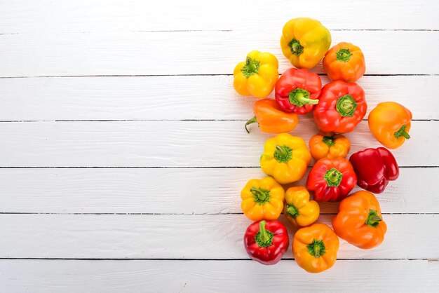 Fresh Colored Paprika Top view On a white wooden background Free space for text