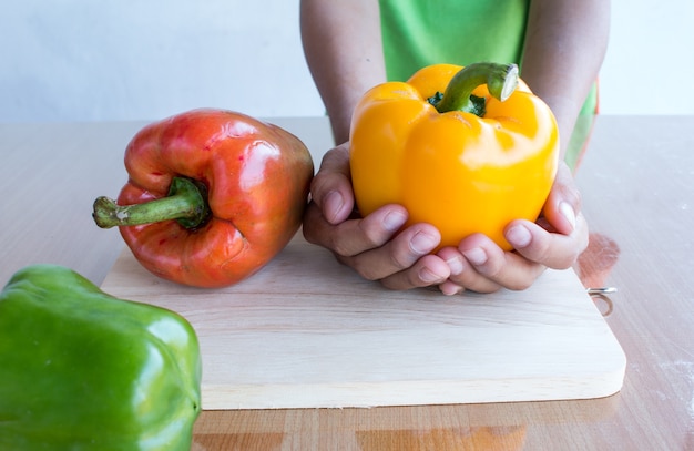 Fresh colorful bell pepper cooking on wooden cut board in kitchen table ready for cook