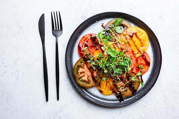 Fresh colorful tomatoes salad with balsamic vinegar on a plate top view