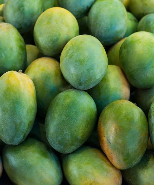 屋外のファーマーズマーケットのクローズアップで展示されている新鮮なカラフルなトロピカルマンゴー。フルーツ。健康的な食事。秋の農業収穫の概念