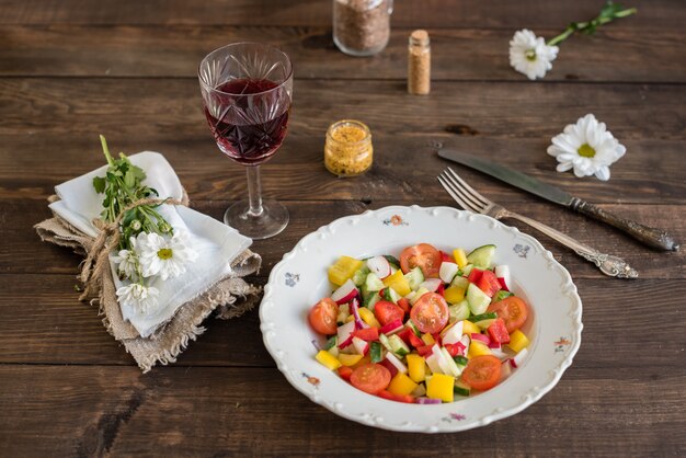 Verdure variopinte fresche su un piatto bianco su un fondo di legno scuro