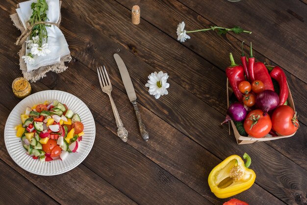 Verdure variopinte fresche su un piatto bianco su un fondo di legno scuro