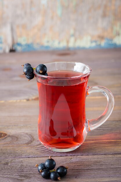 Fresh compote of ripe black currant in a glass on a wooden table