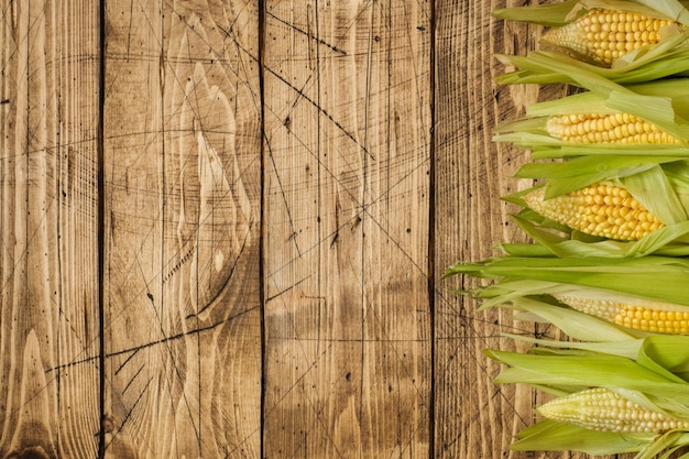 Foto cereale fresco sulle pannocchie sulla tavola di legno rustica, primo piano. copia spazio