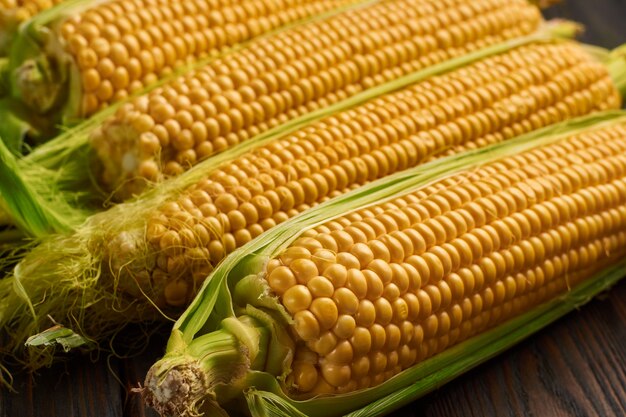 Fresh corn on cobs on rustic wooden table, closeup