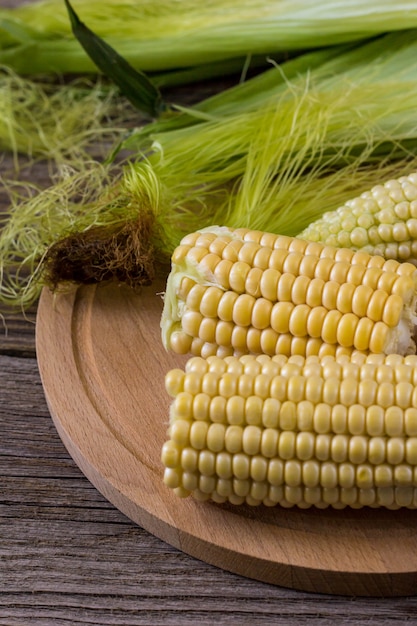 Fresh corn on cobs on rustic wooden table, closeup