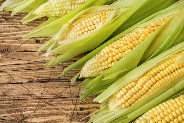 Fresh corn on cobs on rustic wooden table