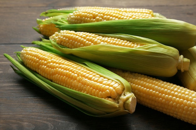 Fresh corn on cobs on wooden table closeup