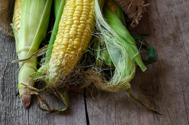 Fresh corn on cobs on wooden table