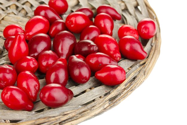 Fresh cornel berries on wicker mat isolated on white