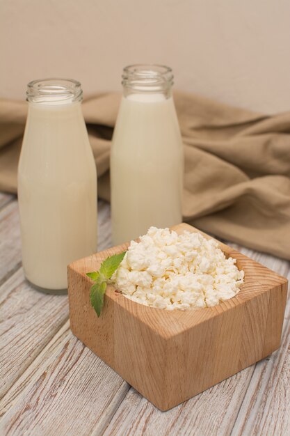 Fresh cottage cheese in a square wooden cup on an old wooden table.