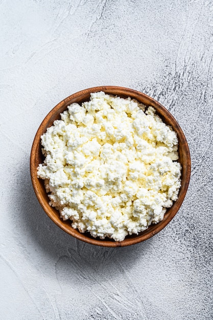 Fresh Cottage cheese in a wooden bowl.  Gray background. Top view