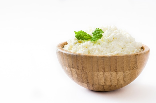 Fresh cottage cheese in a wooden bowl isolated on white