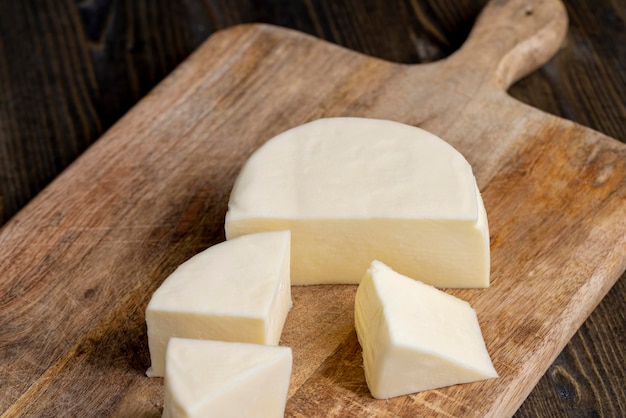 Fresh cow's milk cheese is cut on a board